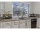 Modern kitchen sink with white cabinets and a window overlooking the pool at 3668 Janus Way, Palm Harbor, FL 34685
