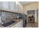 Well-appointed laundry room featuring granite countertops, shaker style cabinets, a mosaic tile backsplash, and modern appliances at 3668 Janus Way, Palm Harbor, FL 34685