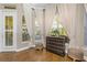 Bright living room featuring hardwood floors, a chest of drawers, and large windows with elegant white curtains and window blinds at 3668 Janus Way, Palm Harbor, FL 34685