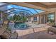A screened in pool with brick surround, a stone water feature and outdoor seating at 3668 Janus Way, Palm Harbor, FL 34685
