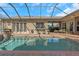 A screened in pool with brick surround, seating and a relaxing outdoor space at 3668 Janus Way, Palm Harbor, FL 34685