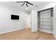 Well-lit bedroom featuring open closet, wood floors, a ceiling fan and tv mounted on the wall at 3815 W Obispo St, Tampa, FL 33629