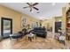 Living room area with travertine tile floors, ceiling fans, leather sofa and black interior door at 403 Indian Meadow Ct, Wimauma, FL 33598