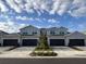 View of the new townhomes with attached garages, gray facade, and beautiful landscaping at 43314 Water Bird Way # 6712, Punta Gorda, FL 33982