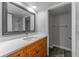 This bathroom features a wood vanity, white countertop and mirror with marble shower in the reflection at 4714 Kemble Ct, Tampa, FL 33624