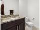 Powder room with dark wood vanity, granite countertop, chrome faucet, and white toilet at 4859 W Prescott St, Tampa, FL 33616