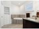 Bathroom with modern soaking tub, tile surround, granite vanity, and built-in storage shelves at 4859 W Prescott St, Tampa, FL 33616