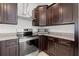 Modern kitchen featuring dark wood cabinetry, granite countertops, stainless steel appliances, and range hood at 4859 W Prescott St, Tampa, FL 33616