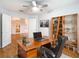 Bright home office features a wood desk, shelving, and view of the entryway and kitchen at 5351 Lookout Pass, Wesley Chapel, FL 33544