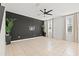 Bright living room with sleek black accent wall, tile flooring, ceiling fan and two large sunny windows at 707 Fern Leaf Dr, Ruskin, FL 33570