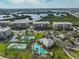 Aerial view of the community featuring tennis courts, a pool, and buildings surrounded by lush greenery and water views at 7194 Key Haven Rd # 405, Seminole, FL 33777