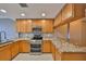 Bright kitchen showcasing wooden cabinetry, granite countertops and modern stainless steel appliances at 7194 Key Haven Rd # 405, Seminole, FL 33777