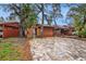 Wide view of stone driveway, garage, carport, palm trees, and a gate to the backyard at 799 Fairwood Ln, Clearwater, FL 33759