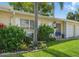 Charming single-story home with a well-maintained lawn, complemented by lush landscaping and bright blue patio chairs at 858 Cambridge Ct # 858, Dunedin, FL 34698