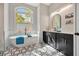 Elegant bathroom with a freestanding tub, arched window, dual vanities and black and white patterned tile at 10218 Garden Alcove Dr, Tampa, FL 33647