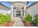 Elegant home entrance featuring a charming walkway, complemented by lush landscaping and classic architectural details at 10218 Garden Alcove Dr, Tampa, FL 33647