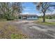 Single story home with attached garage and large gravel driveway and mature trees at 1051 Hawthorn St, Zephyrhills, FL 33540