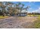 Exterior view of a single-story home with a detached garage and a large unpaved driveway at 1051 Hawthorn St, Zephyrhills, FL 33540