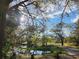 Scenic view of a pond reflecting the sky, surrounded by lush greenery and mature trees along a dirt road at 1051 Hawthorn St, Zephyrhills, FL 33540