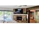 Bright living room featuring a stone fireplace, TV, and access to outdoor deck at 1102 Old Mill Pond Rd, Palm Harbor, FL 34683