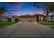 Beautiful single-story home during dusk with a well-manicured lawn and a spacious driveway leading to a two-car garage at 1220 Emerald Hill Way, Valrico, FL 33594