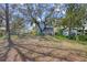 Spacious backyard featuring a charming blue home with a screened porch, mature trees, and a large open area at 12227 Noreast Lake Dr, Tampa, FL 33612