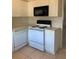 Compact kitchen featuring white cabinets, black microwave, and white appliances at 12403 Hibiscus Oak Pl # 202, Tampa, FL 33612