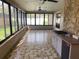 Bright sun room with stone accent wall, tile flooring, windows overlooking the backyard, and convenient kitchen area at 13304 Meadowwood Ct, Tampa, FL 33618