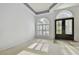 Bright living room featuring a decorative front door, arched windows, and neutral carpet at 15209 Hammock Chase Ct, Odessa, FL 33556