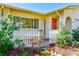 Inviting front entrance with a bright orange door, charming white picket fence, and beautiful landscaping enhancing curb appeal at 1831 Kay Dr, Largo, FL 33770