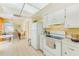 Functional kitchen with white appliances and cabinets, adjacent to a dining area with natural light at 1831 Kay Dr, Largo, FL 33770