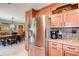 Kitchen area with stainless steel refrigerator, view of the dining room table, and custom wood cabinetry at 2504 Woodcote Ter, Palm Harbor, FL 34685