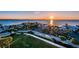 Panoramic aerial view showcases waterfront homes with palm trees, and lush lawns under a stunning sunset backdrop at 2530 Gary Cir # 401, Dunedin, FL 34698