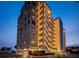 Exterior view of the condo building, Marina Tower, at dusk with lights on and covered parking with several cars at 2530 Gary Cir # 401, Dunedin, FL 34698