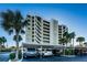 View of the Marina Tower condo building with parking and palm trees in the foreground under a bright blue sky at 2530 Gary Cir # 401, Dunedin, FL 34698