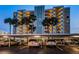 Exterior view of the condo building, Marina Tower, at dusk with lights on and covered parking with several cars at 2530 Gary Cir # 401, Dunedin, FL 34698