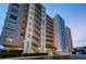 Exterior view of the condo building, Marina Tower, at dusk with lights on and landscaping at 2530 Gary Cir # 401, Dunedin, FL 34698