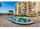 Condo pool area with chairs and tables surrounding the blue pool, and the condo building in the background at 2530 Gary Cir # 401, Dunedin, FL 34698
