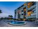 Exterior shot of building at dusk and pool with palm trees, with lighted windows and balconies at 2530 Gary Cir # 401, Dunedin, FL 34698