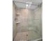 Modern shower with glass door, neutral stone tile, built in shelves, and rainfall shower head at 2530 Gary Cir # 401, Dunedin, FL 34698