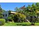 Condo building featuring lush greenery, palm trees, and an American flag at 3300 Fox Chase N Cir # 229, Palm Harbor, FL 34683