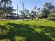 Scenic front yard with lush green grass and trees displaying an American flag in the background at 3300 Fox Chase N Cir # 229, Palm Harbor, FL 34683