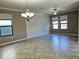 Spacious living room featuring tile floors, a decorative wall, a modern light fixture, and bright windows at 3367 Janna Grace Way, Land O Lakes, FL 34638