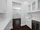 Butler's pantry with white cabinets, mosaic backsplash, wine cooler, and view to living room at 3709 W Dale Ave, Tampa, FL 33609