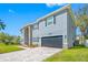 Front exterior of a gray home featuring a stone facade, driveway and manicured lawn at 3709 W Dale Ave, Tampa, FL 33609