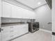 Modern laundry room with white cabinets, grey countertops, stainless steel appliances and light tile flooring at 3709 W Dale Ave, Tampa, FL 33609