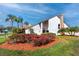 Exterior view of Heritage Lake Clubhouse showcasing landscaping, shrubbery, and palm trees at 4614 Sandpointe Dr, New Port Richey, FL 34655