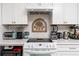Well-lit kitchen with white cabinets, mosaic backsplash, and modern appliances on a white countertop at 4614 Sandpointe Dr, New Port Richey, FL 34655