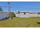 A backyard shed is framed by a white fence with a small lawn, shrubs, and blue sky at 5125 34Th N Ave, St Petersburg, FL 33710