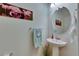 Charming powder room featuring pedestal sink, round mirror, flamingo art, and a wall-mounted towel rack at 5312 Sylvester Loop, Tampa, FL 33610